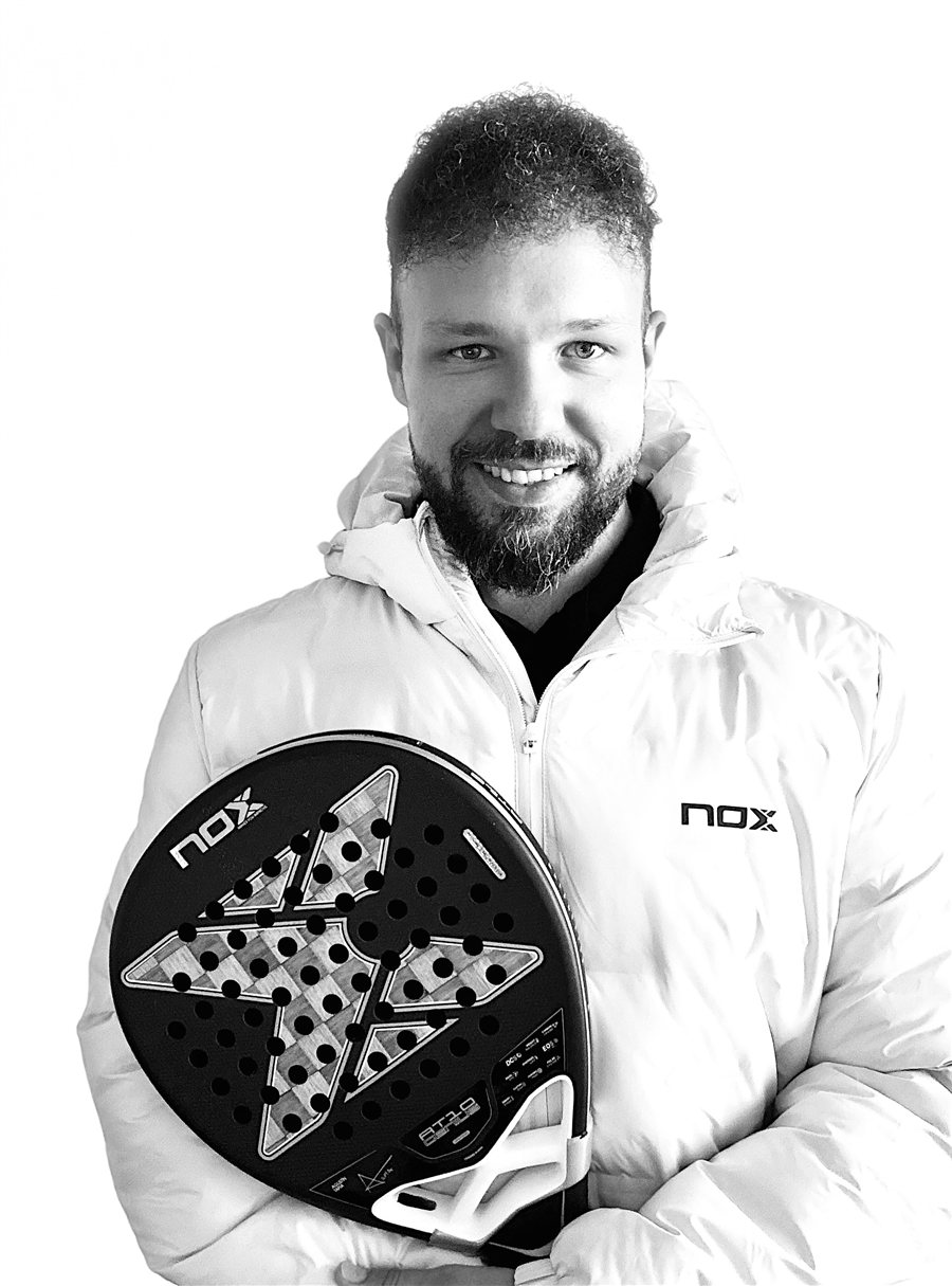 Felix Gutsmann, Padel-Trainer, lächelnd mit Padel-Schläger in weißer Jacke